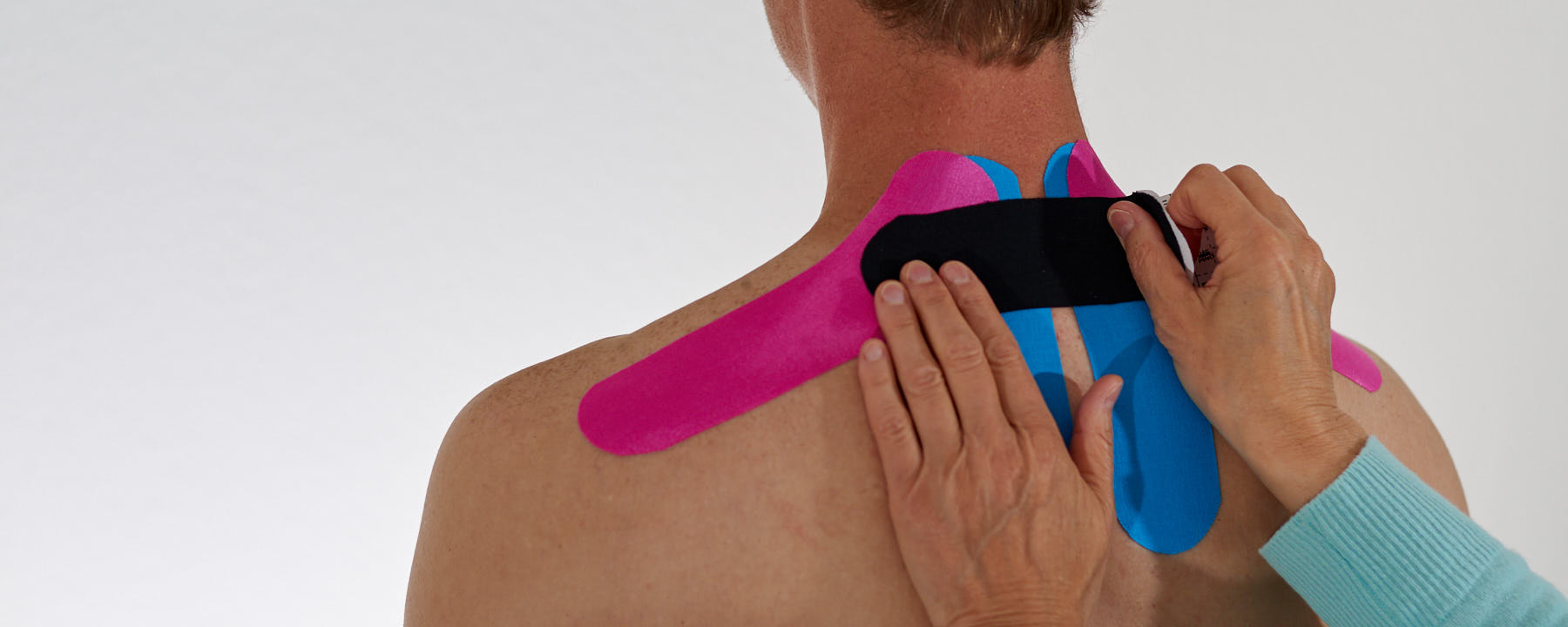 Anbringung eines Kinesiotape im Nacken- / Schulterbereich eines Patienten